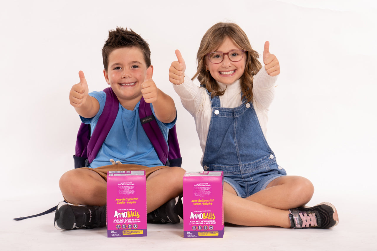 Photo of school children with thumbs up next to amino balls snacks